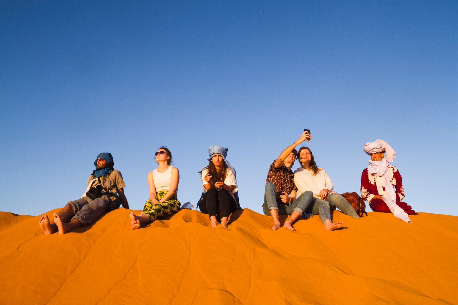 Marokko Explore Tours group people sitting top dune scaled